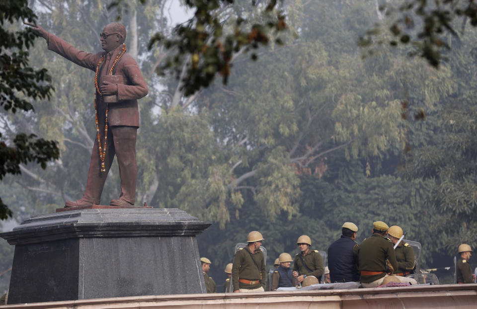 Policemen guard near a statue of Bhim Rao Ambedkar in Lucknow, Uttar Pradesh state, India, Sunday, Dec. 22, 2019. Violent protests against India's citizenship law that excludes Muslim immigrants have swept the country over the weekend despite the government's ban on public assembly and suspension of internet services in many parts. Police said nine people died in clashes with security forces in Uttar Pradesh on Saturday, most of them young protesters. (AP Photo/Rajesh Kumar Singh)