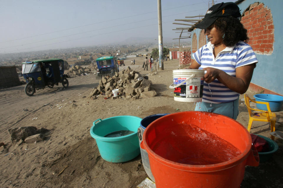 Lima, PERU:  Una mujer saca agua de un recipiente por el cual pago 0.50 centavos de dolar, debido a la falta de agua potable en el asentamiento de Lomo de Corvina el 02 de junio de 2006 en Lima. Durante los ultimos 4 anos la tasa de pobreza a nivel nacional se redujo en 2,7 puntos porcentuales, al pasar de 54% en 2001 a 51% en el 2004. Casi 30% de los hogares peruanos con ninos y adolecentes tiene una dieta con deficit en calorias, revelo un informe del Instituto de estadisticas e informatica (Ine). AFP PHOTO MARTIN BERNETTI  (Photo credit should read MARTIN BERNETTI/AFP/Getty Images)