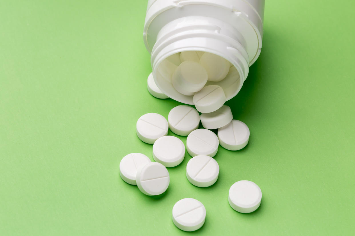 Heap of round white tablets and plastic pills bottle