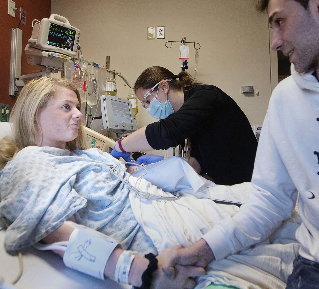 Kylie Allen-Kulyk, left, looks at Ian Pack as Donna Irish, R.N., inserts a needle into Allen-Kulyk's upper arm to begin plasma-replacement treatment in this 2021 file photo taken at UPMC Hamot. Allen-Kulyk is currently in remission and works part time as a phlebotomist.