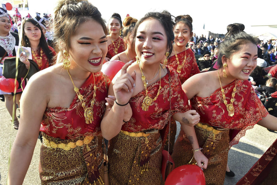 In this photo taken Dec. 26, 2017, from left front, Kathy Vang, Suleka Cha, and Der Vue, McLane High students have fun as they walk in the grand opening parade during the Hmong Cultural New Year Celebration at the fairgrounds in Fresno, Calif. The country's small Hmong American population is reeling from the shooting deaths of four men at a backyard party at a Northern California central valley city. Fresno hosts a week-long New Year's party every year that draws tens of thousands of Hmong from around the country, complete with colorful traditional dress, song, and sports games. (John Walker/The Fresno Bee via AP)
