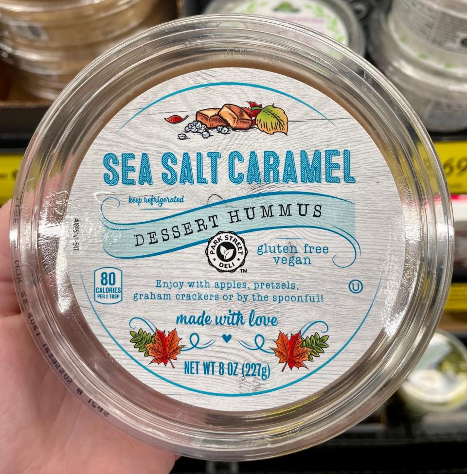 hand holding clear and white tub of sea-salt caramel hummus