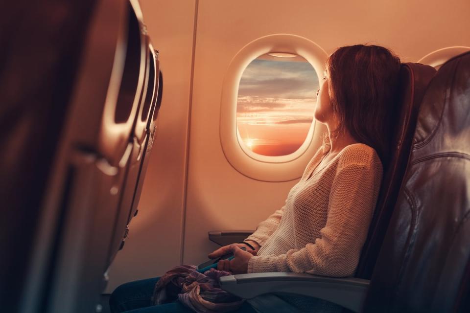 A passenger looks out the window on an airplane.