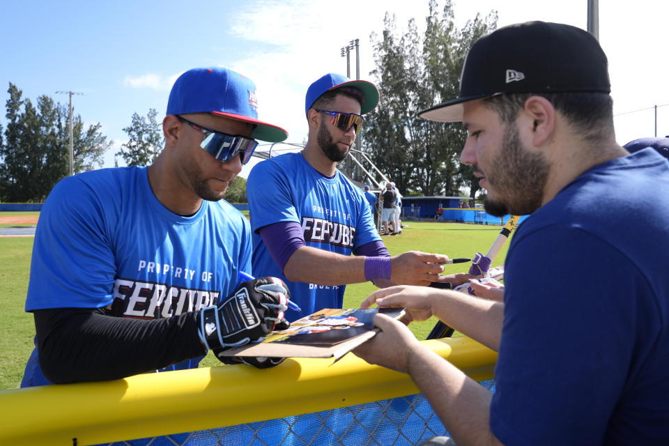 Yuli Gurriel, left, and Lourdes Gurriel Jr., center, sign autographs during practice with the Cuban Professional Baseball Federation (FEPCUBE), Tuesday, Jan. 16, 2024, in Miami. The team is a group of about 30 or so players, most of whom were born in Cuba and defected from their home island. They’re not affiliated with the Baseball Federation of Cuba (FCB), the sport’s governing body in Cuba, but were put together to field a team that represents the patriotic ideals of their people. (AP Photo/Lynne Sladky)