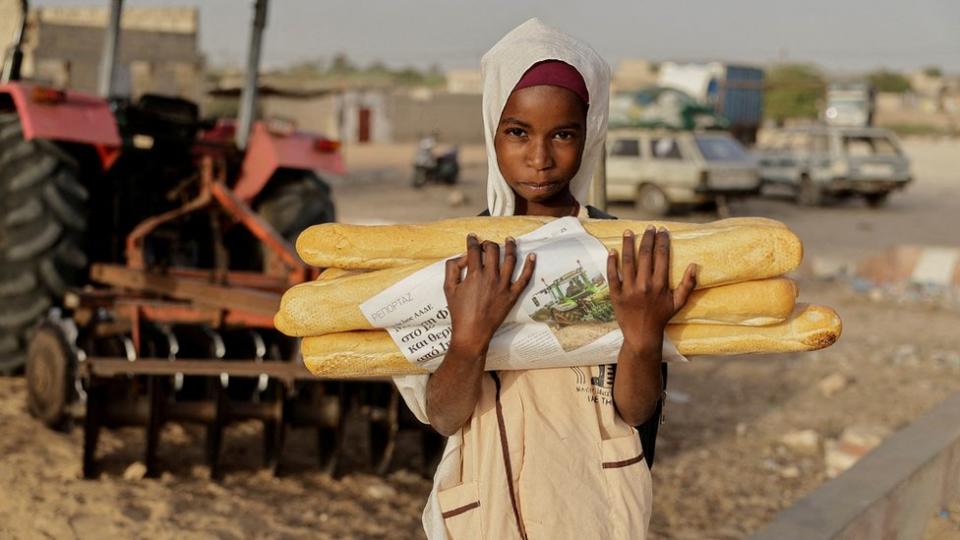 A child carries bread ahead of breaking the fast, during the Muslim holy month of Ramadan, in Fass Boye, Senegal, March 19, 2024.