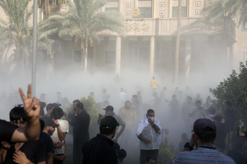 Iraqi security forces fire tear gas on followers of Shiite cleric Muqtada al-Sadr protesting inside the government palace grounds, in Baghdad, Iraq, Monday, Aug. 29, 2022. Al-Sadr, a hugely influential Shiite cleric announced he will resign from Iraqi politics and his angry followers stormed the government palace in response. The chaos Monday sparked fears that violence could erupt in a country already beset by its worst political crisis in years. (AP Photo/Hadi Mizban)