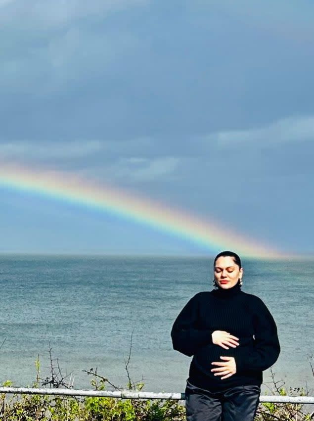 Pregnant Jessie J in front of a rainbow