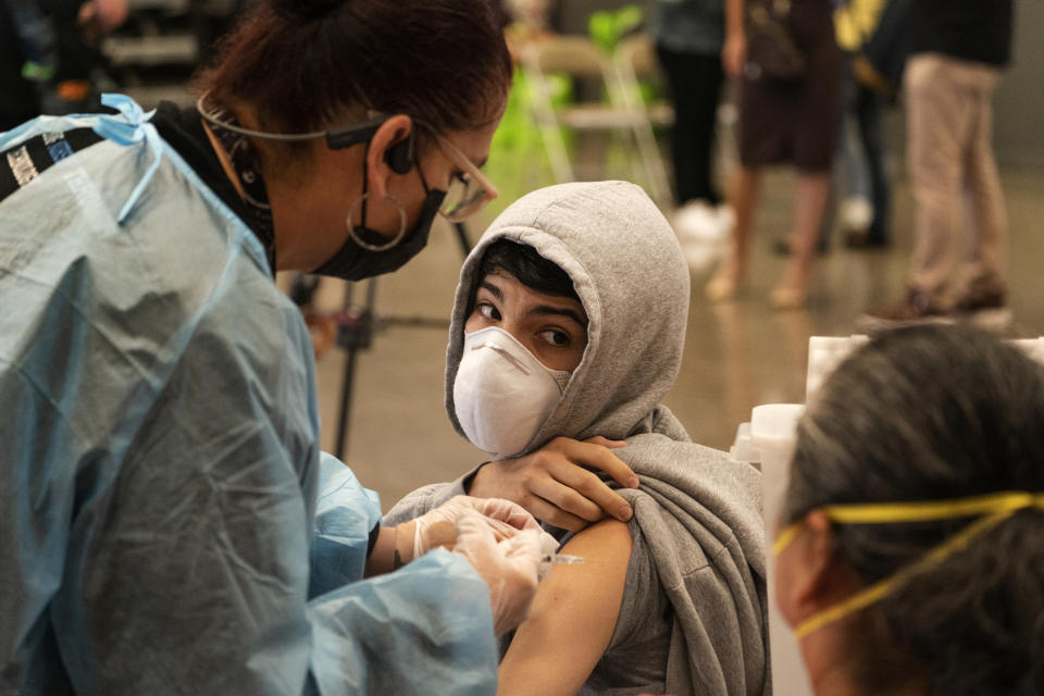 A student looks back at his mother, as he is vaccinated at a school-based COVID-19 vaccination clinic for students 12 and older in San Pedro, Calif., Monday, May 24, 2021. Schools are turning to mascots, prizes and contests to entice youth ages 12 and up to get vaccinated against the coronavirus before summer break. (AP Photo/Damian Dovarganes)