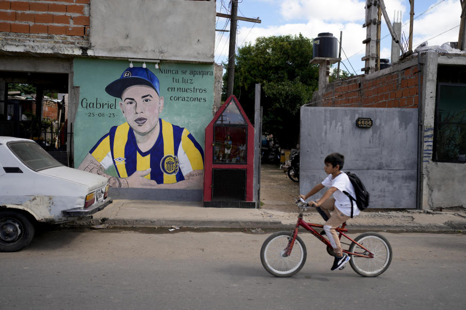 Un niño monta en bicicleta junto a un mural de Gabriel Ignacio Romero, un vecino asesinado el año anterior en la acera delante de su casa, en Rosario, Argentina, el lunes 8 de abril de 2024. En la última década, los 1,3 millones de habitantes de Rosario han visto pasar con a sucesivos presidentes y sus promesas. Lo que permanece, dicen, es la violencia. (AP Foto/Natacha Pisarenko)