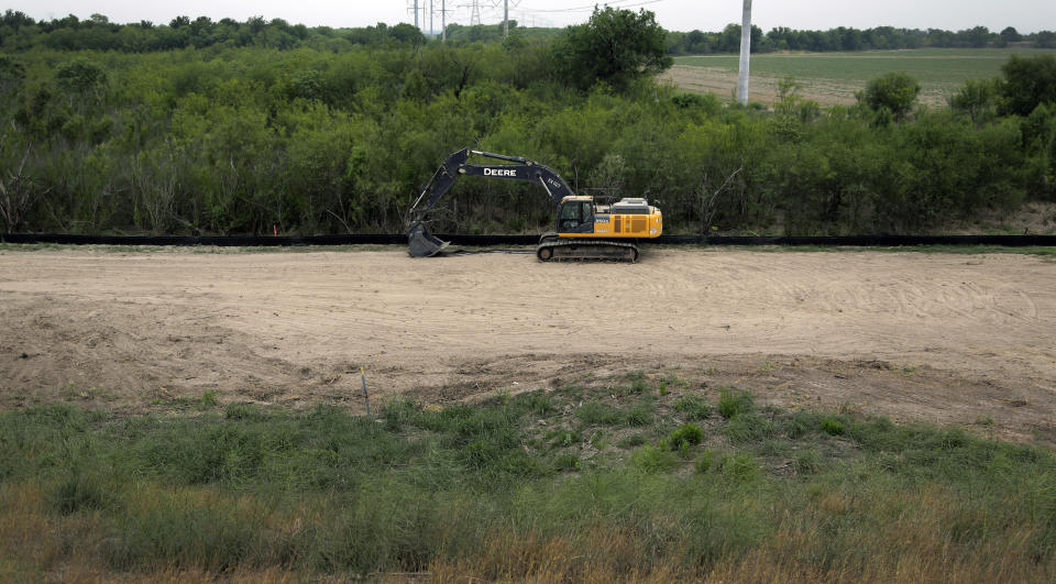 FILE - In this April 29, 2019, file photo, construction equipment sets in an area of demolished trees and brush where construction is set to begin soon, in Mission, Texas. Three years into Donald Trump's presidency, the U.S. government is finally ramping up its efforts to seize the private land it needs to build a border wall in South Texas.(AP Photo/Eric Gay File)
