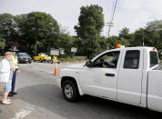 A Columbia Gas truck passes through a roadblock as a member of the State Police talks to a pedestrian on Route 114 in North Andover, Mass., at the Lawrence city line, Friday, Sept. 14, 2018. Many roads remain closed after Thursday afternoon gas explosions and fires triggered by a problem with a gas line that feeds homes in several communities north of Boston. (AP Photo/Mary Schwalm)