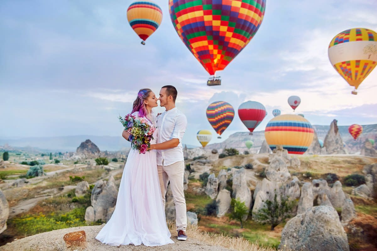 A couple tie the knot with hot air balloons all around them.