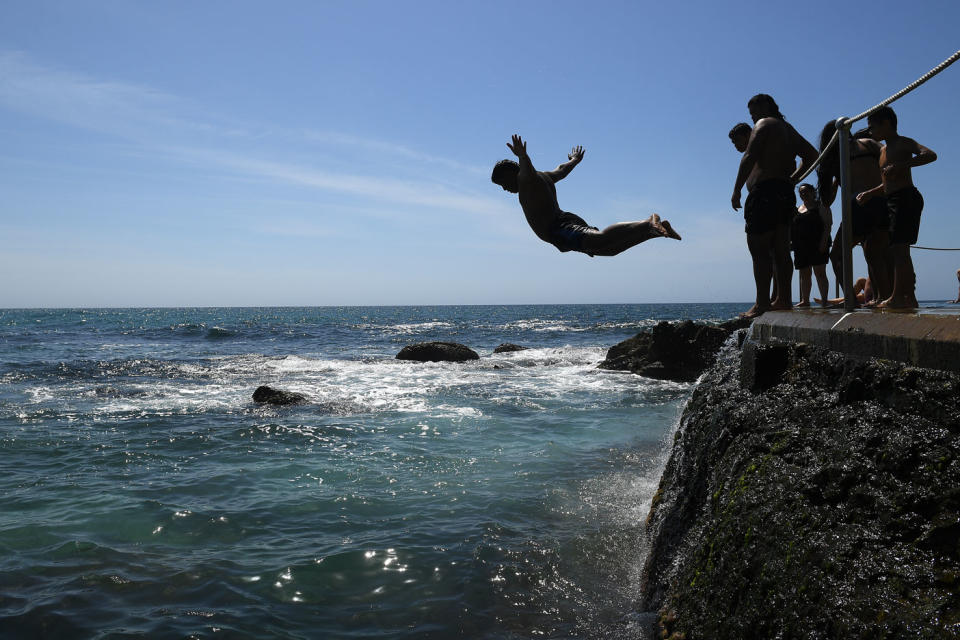 Boys jump from rocks into ocean.