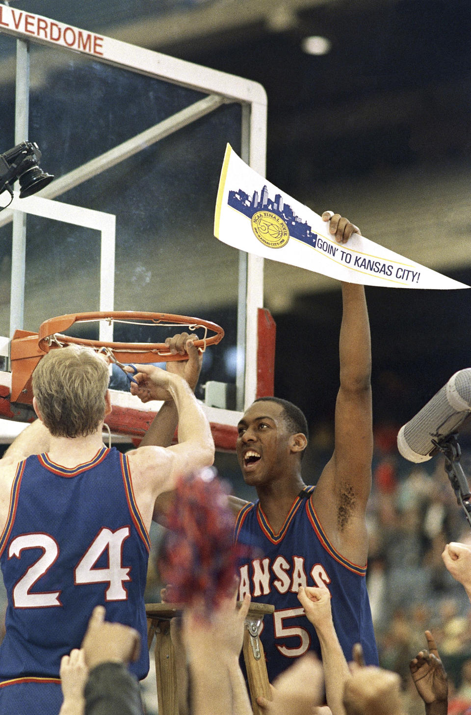 FILE - Kansas' Danny Manning hoists a banner aloft as teammate Chris Piper cuts the net after the Jayhawks beat Kansas State 71-58 to win the Midwest Regional Final Sunday, March 27, 1988, at the Pontiac Silverdome in Pontiac, Mich. Once the Jayhawks got to the NCAA Tournament, Manning carried them to their second national title.(AP Photo/Al Behrman, File)