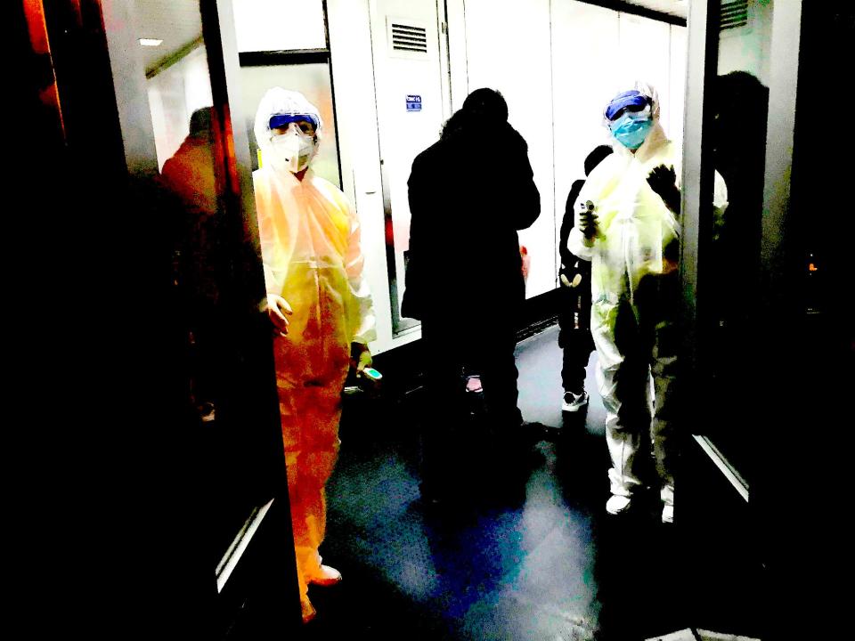 Health Officials in hazmat suits wait at the gate to check body temperatures of passengers arriving from the city of Wuhan Wednesday, Jan. 22, 2020, at the airport in Beijing, China.