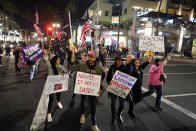 Demonstrators march across Pacific Coast Highway while shouting slogans Saturday, Nov. 21, 2020 during a protest against a stay-at-home order amid the COVID-19 pandemic in Huntington Beach, Calif. California health officials are restricting overnight activities starting Saturday night, though there are plenty of exceptions. They're calling it a limited stay-at-home order designed to stem the rapidly spreading coronavirus by discouraging social gatherings. (AP Photo/Marcio Jose Sanchez)