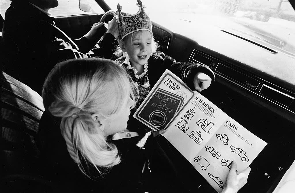 Girls Read Travel Guide On Car Trip.