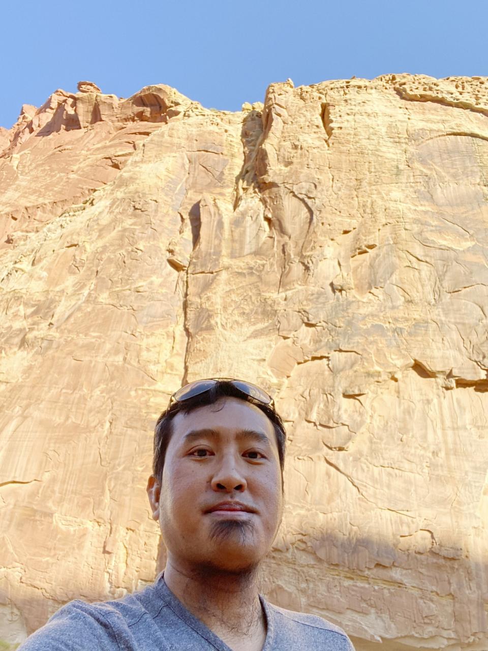 In this Aug. 15, 2020, photo provided by Lian Kual, resettled refugee Kual, originally from Myanmar, stands against a rock wall in the Capitol Reef National Park in Utah, the state where he now lives. Kual, who was naturalized earlier this year, said he is looking forward to voting in the U.S. presidential election after growing up in a country that had no democratic culture during decades of military rules. (Lian Kual via AP)