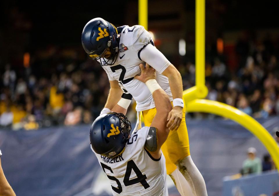 Dec 28, 2021; Phoenix, AZ, USA; West Virginia Mountaineers quarterback Jarret Doege (2) celebrates a touchdown with offensive lineman Zach Frazier (54) against the Minnesota Golden Gophers in the first half of the Guaranteed Rate Bowl at Chase Field. Mandatory Credit: Mark J. Rebilas-USA TODAY Sports