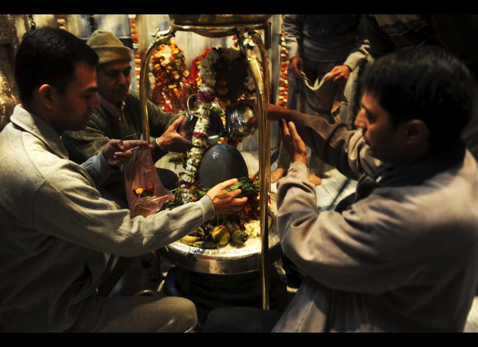 Indian Hindu devotees pour milk over a Shiva Lingam, a stone deity sculpture representing the creative energy of the Universe and the infinite nature of Shiva.&nbsp;