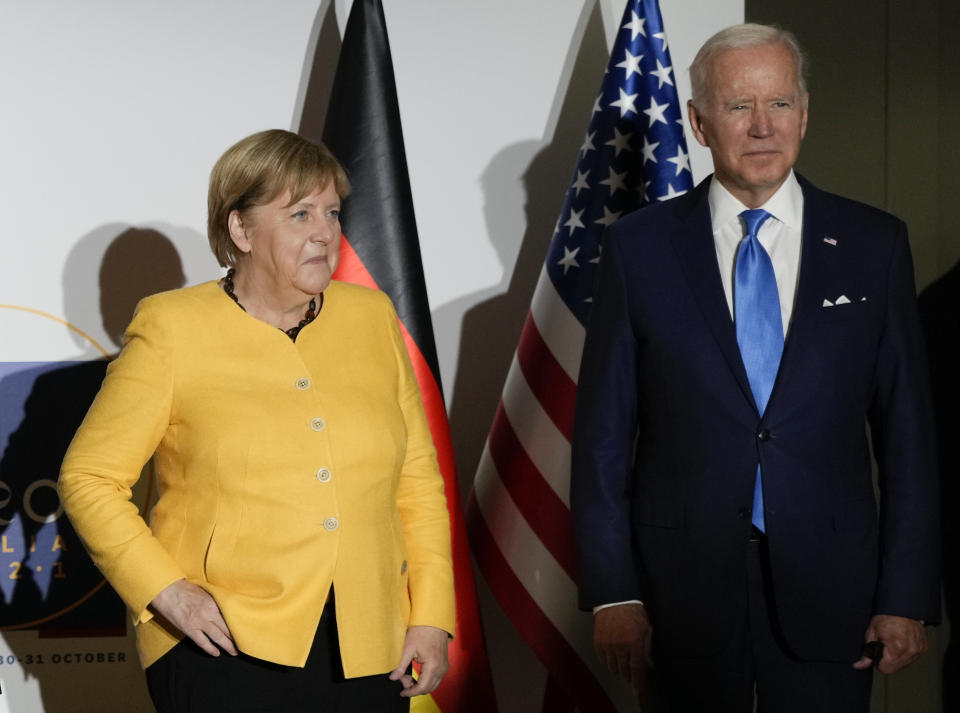 German Chancellor Angela Merkel, left, and U.S. President Joe Biden pose for the media at the La Nuvola conference center for the G20 summit in Rome, Saturday, Oct. 30, 2021. The two-day Group of 20 summit is the first in-person gathering of leaders of the world's biggest economies since the COVID-19 pandemic started. (AP Photo/Kirsty Wigglesworth, Pool)