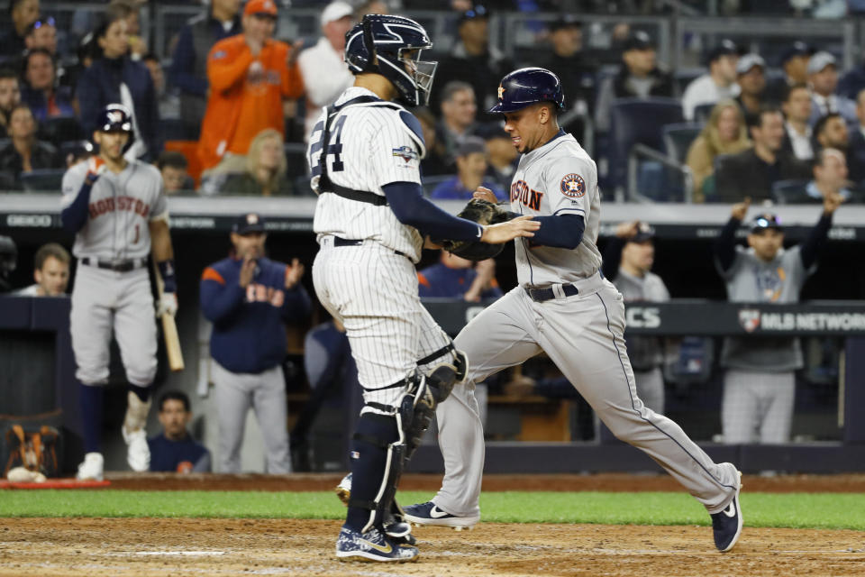 Houston Astros' Michael Brantley, right, scores past New York Yankees catcher Gary Sanchez on a sacrifice fly by Yuli Gurriel during the seventh inning in Game 3 of baseball's American League Championship Series Tuesday, Oct. 15, 2019, in New York. (AP Photo/Matt Slocum)