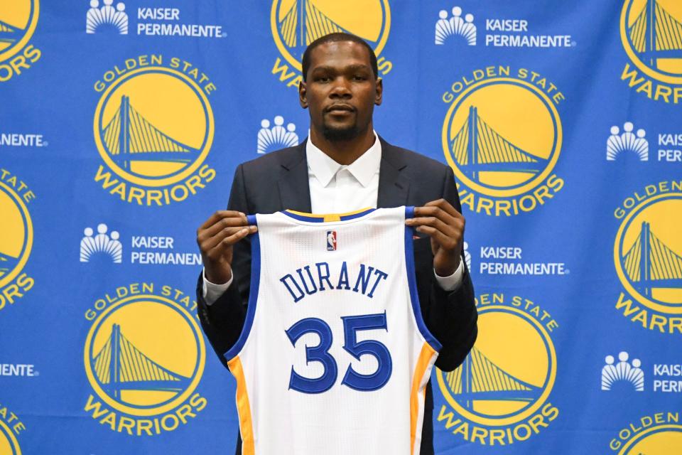 Kevin Durant poses for a photo with his jersey during a press conference after signing with the Golden State Warriors in 2016.