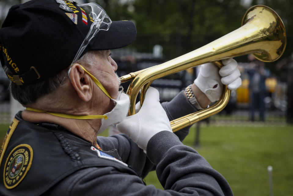 A bugler plays Taps as a motorcade of veterans stops outside the VA Medical Center for a wreath laying ceremony beside memorial stones on the premises, Monday, May 25, 2020, in the Brooklyn borough of New York. (AP Photo/John Minchillo)