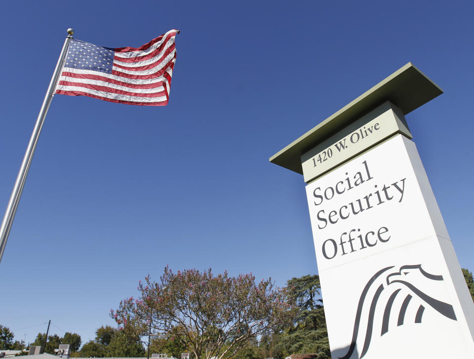 An American flag flutters in the wind next to signage for a United States Social Security Administration office in Burbank, California October 25, 2012. REUTERS/Fred Prouser (UNITED STATES - Tags: POLITICS SOCIETY IMMIGRATION)