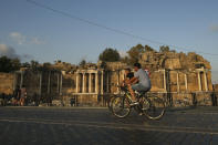 Tourists ride their bicycles in front of an ancient site in Antalya, southern Turkey, on Sunday, June 20, 2021. Hotels in Turkey's Antalya region, a destination beloved by holidaymakers, are preparing to finally resume operations as they expect the return of international tourists after months of setbacks caused by the pandemic that halted travel. (AP Photo/Emrah Gurel)