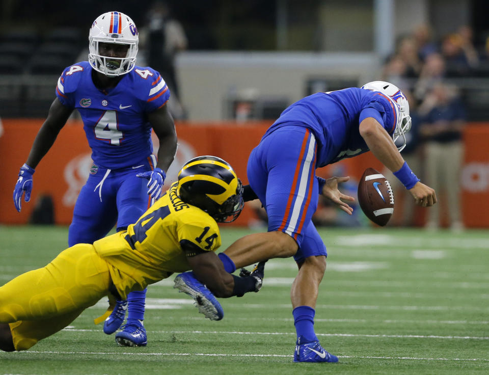 Michigan safety Josh Metellus (14) strips the ball from Florida quarterback Feleipe Franks (13) after a short run by Franks as wide receiver Brandon Powell (4) watches in the second half of an NCAA college football game, Saturday, Sept. 2, 2017, in Arlington, Texas. (AP Photo/Tony Gutierrez)