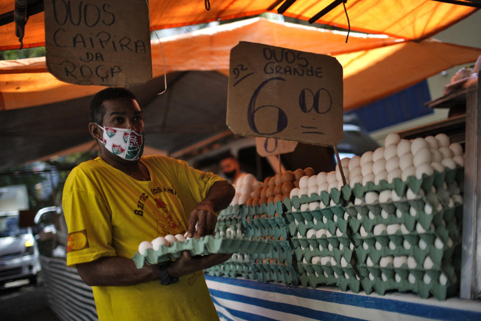 A man wearing a face mask of Brazils football team Fluminense prepares eggs for sale after street markets were reopened in Rio de Janeiro, Brazil on April 29, 2020, amid the new coronavirus pandemic. - Rio de Janeiro's municipality authorized the reopening of street markets but under safety measures as the use of alcohol gel, face masks and keeping a distance of two meters between each stand. (Photo by Mauro Pimentel / AFP) (Photo by MAURO PIMENTEL/AFP via Getty Images)