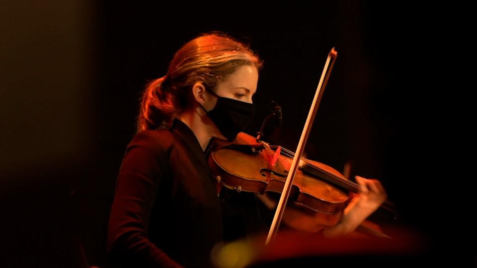 Violinist  Julia Noone, Louisville Orchestra assistant concertmaster. To continue performing during the pandemic, The Louisville Orchestra has moved to Paristown Hall and is practicing social distancing on stage, masked instruments (and performers) plexiglass barriers between musicians plus an altered configuration of where musicians are seat.