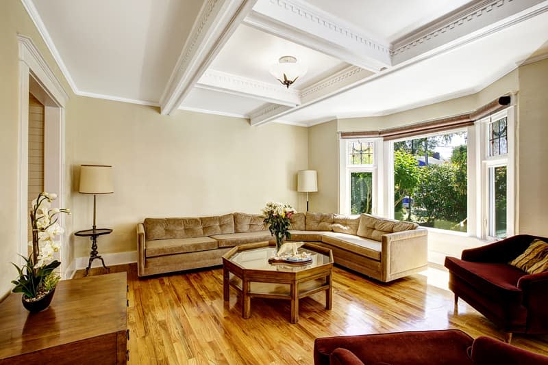 Bright living room with coffered ceiling system, hardwood floor and round window