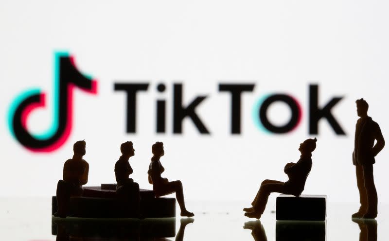Small toy figures are seen in front of a Tiktok logo in this illustration taken