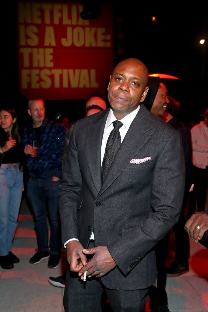 Man in a gray suit stands at a Netflix event with a crowd behind