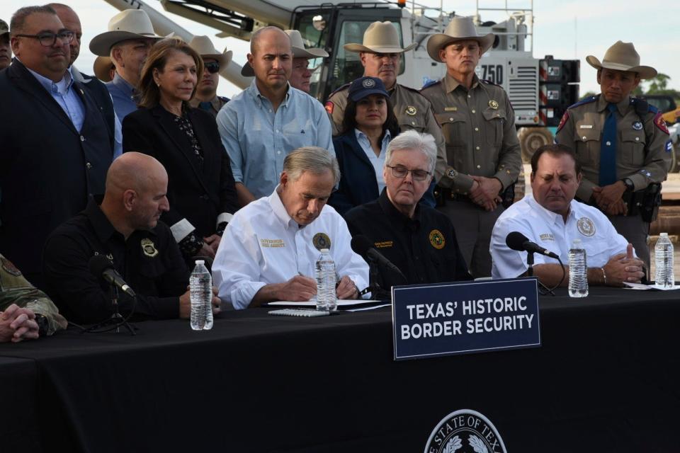 Gov. Greg Abbott signs three bills into law at a border wall construction site in Brownsville, Texas on Monday, Dec. 18, 2023, that will broaden his border security plans and add funding for more infrastructure to deter illegal immigration. (AP Photo/Valerie Gonzalez)