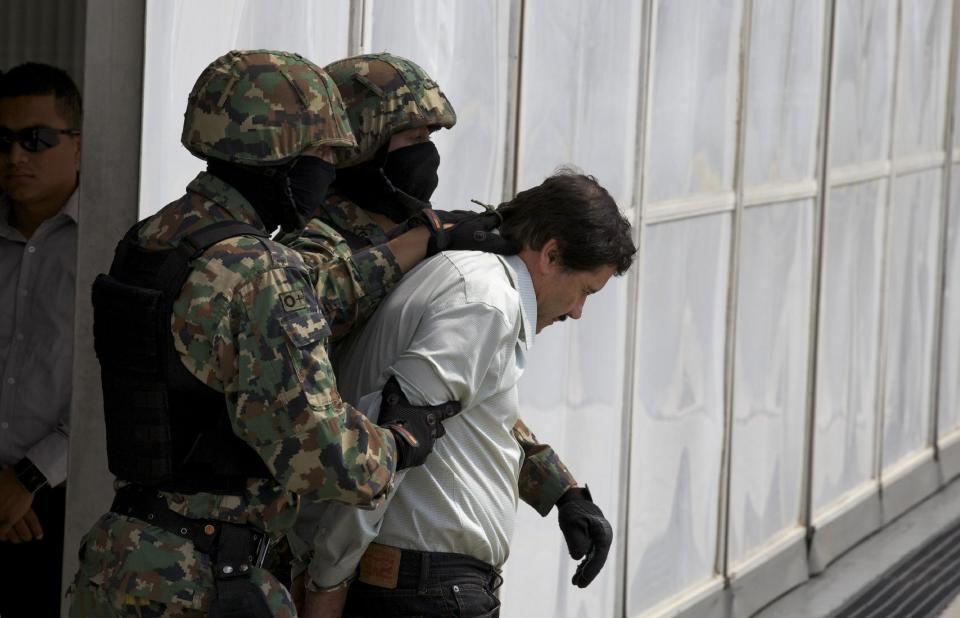 Joaquin "El Chapo" Guzman is escorted to a helicopter in handcuffs by Mexican navy marines at a navy hanger in Mexico City, Saturday, Feb. 22, 2014. (AP Photo/Dario Lopez-Mills)