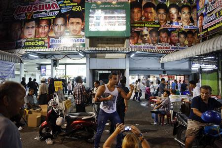 A tourist pose for a picture after the closing Thai boxing, or "Muay Thai", fight night of the legendary Lumpinee stadium, one of Bangkok's oldest boxing venues which is being demolished after 57 years, February 7, 2014. REUTERS/Damir Sagolj