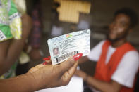 A woman displays her vote card before casting her votes in the presidential election in Lome, Togo, Saturday, Feb. 22, 2020. The West African nation of Togo is voting Saturday in a presidential election that is likely to see the incumbent re-elected for a fourth term despite years of calls by the opposition for new leadership. (AP Photo/Sunday Alamba)