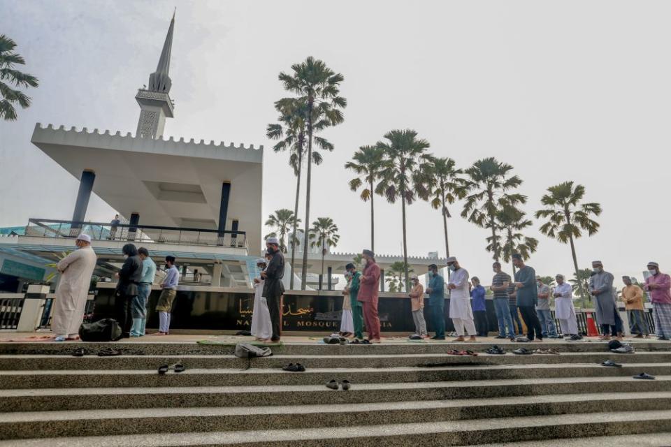 Muslims perform Eid Al-Fitr prayers outside the National Mosque before being told to leave by the police in Kuala Lumpur May 24, 2020 — Picture by Firdaus Latif