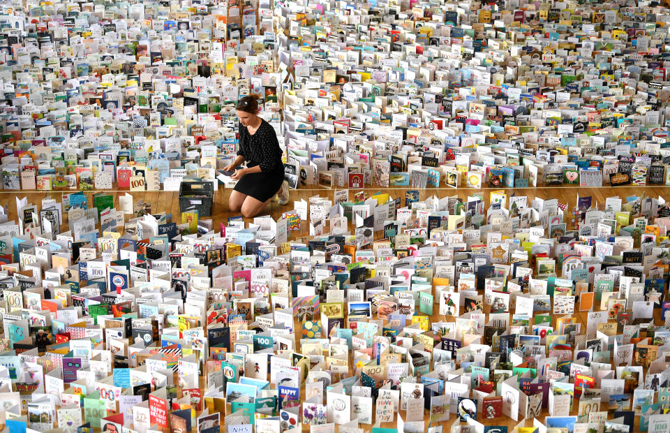 BEDFORD, ENGLAND - APRIL 29:  Mandy Alison adds to the thousands of birthday cards sent to Captain Tom Moore for his 100th birthday on April 30th, are pictured displayed in the Hall of Bedford School, closed-down due to the COVID-19 pandemic, in Bedford, on April 29, 2020. - 99-year-old Moore raised just money for Britain's National Health Service (NHS) following the novel coronavirus outbreak, by walking 100 laps of his garden. (Photo by Shaun Botterill/Getty Images)