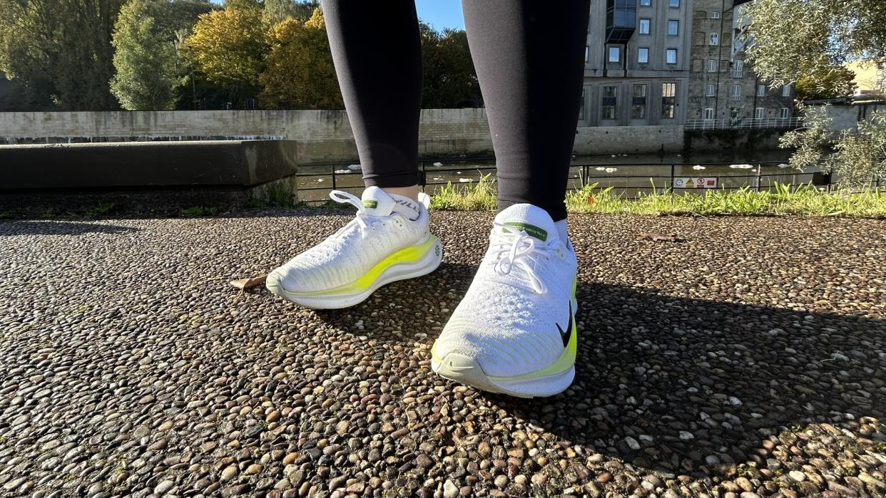  Woman's feet wearing Nike Infinity Run Flyknit 4 road running shoes - front view. 