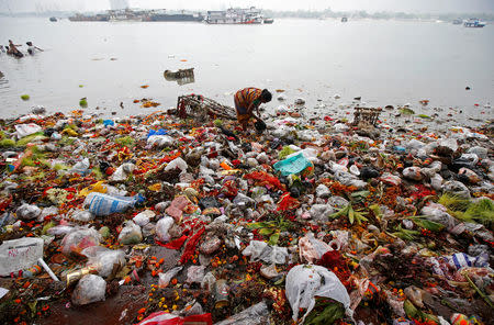 FILE PHOTO: A woman collects items thrown by devotees as religious offerings in the Ganges river, after the celebrations of the last day of Navratri festival, in Kolkata, India, March 26, 2018. REUTERS/Rupak De Chowdhuri/File photo