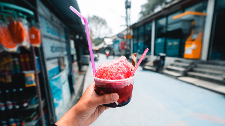 person holding up cup of red shaved ice