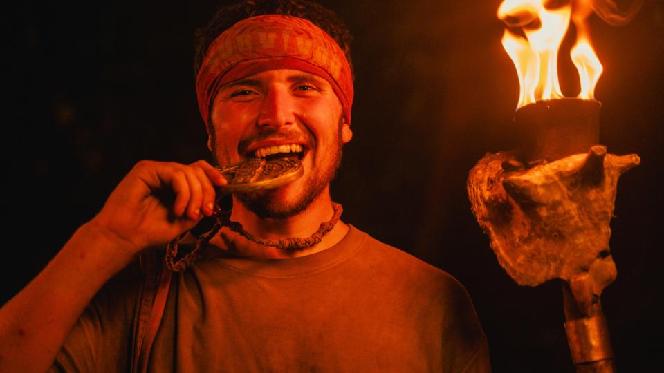 Matthew bites his medal after being crowned the Survivor UK Sole Survivor