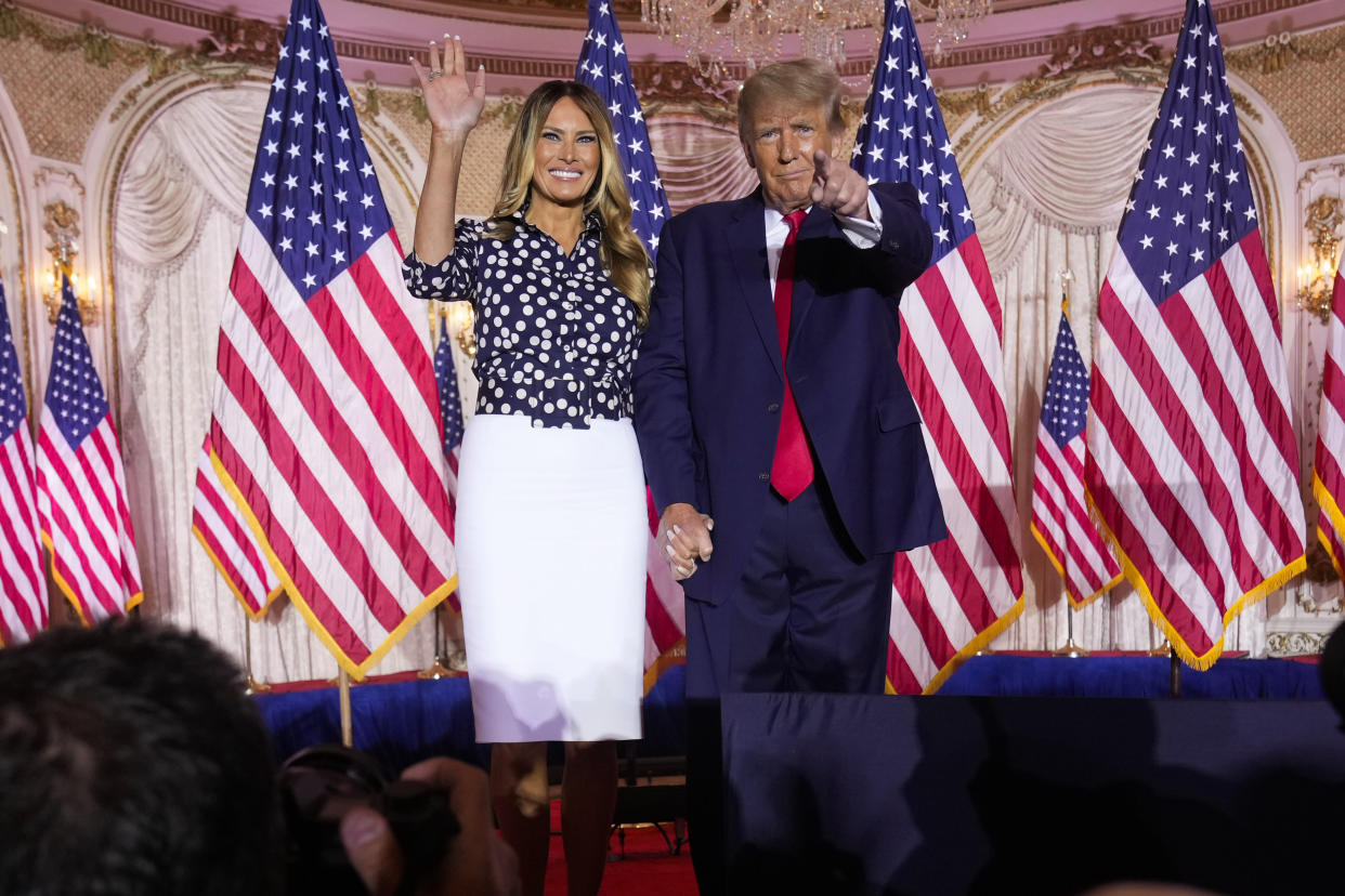 Donald Trump, right, stands onstage, backgrounded by U.S. flags, with Melania Trump in 2022.