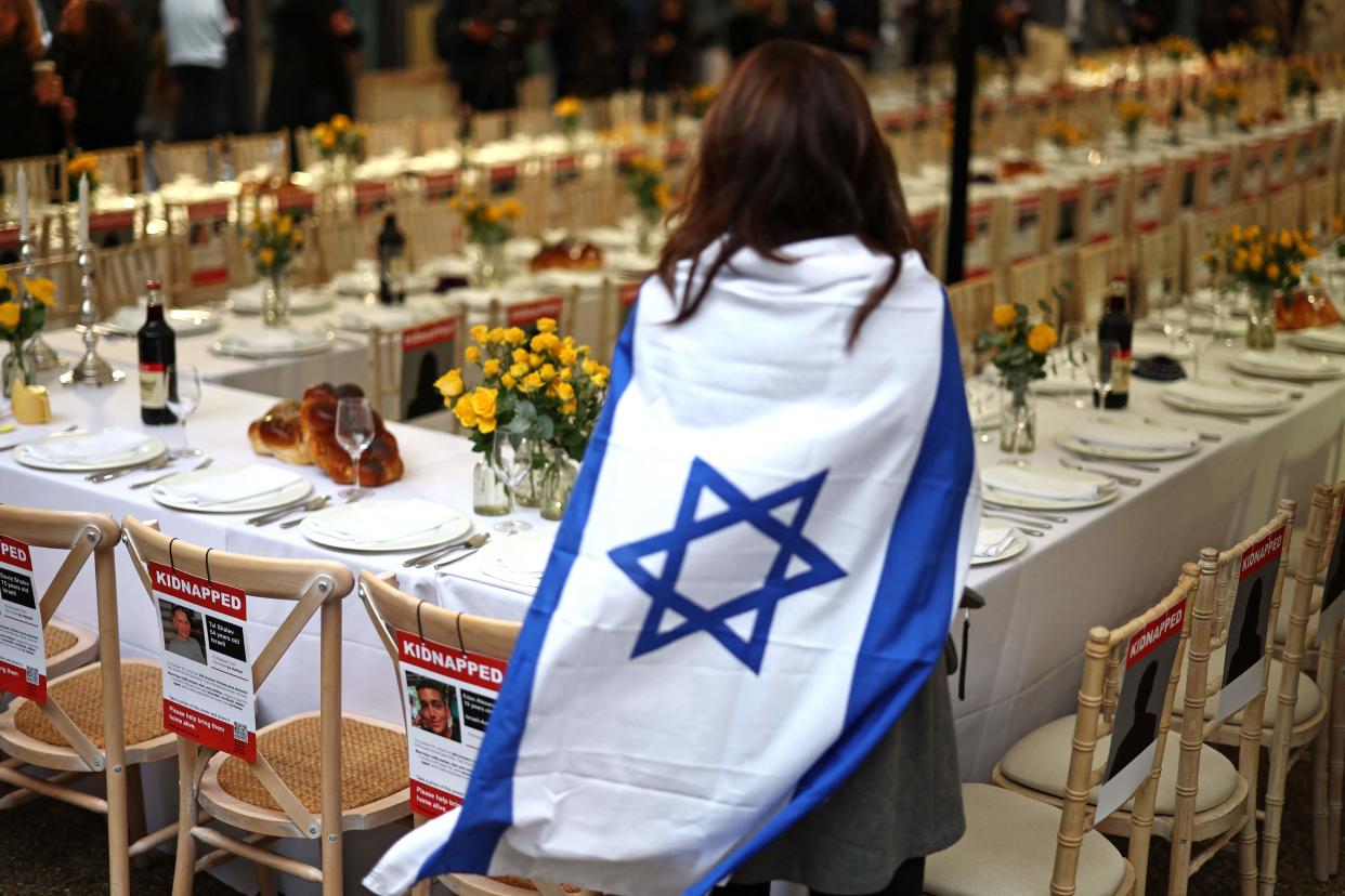 A woman with an Israeli flag visits the empty Shabbat table installation in London (AFP via Getty Images)