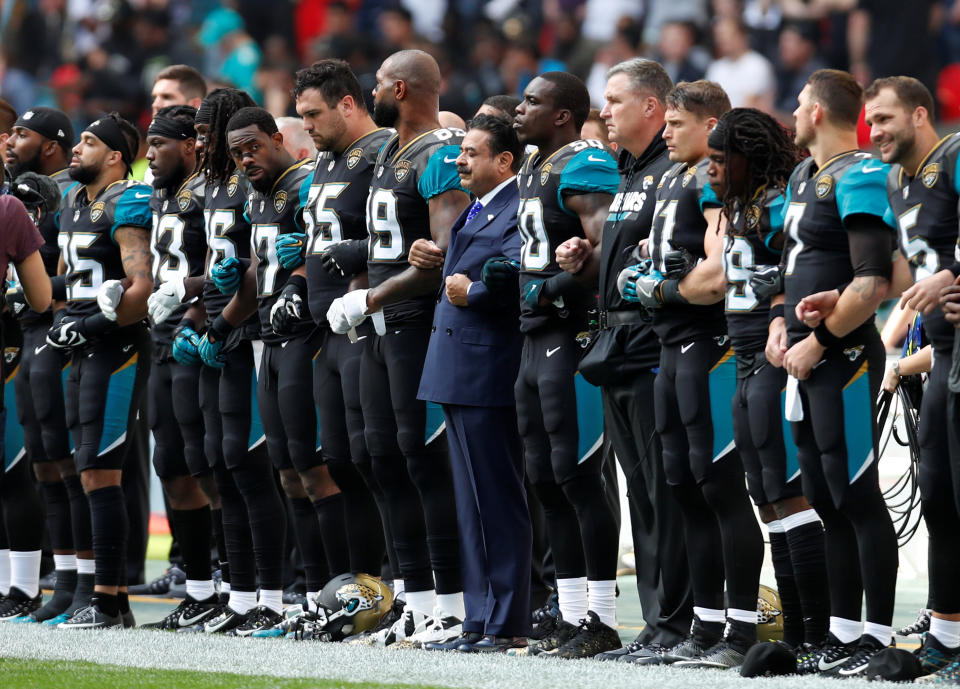 Jaguars owner Shad Khan links arms with players during the national anthem before the game. (Reuters)