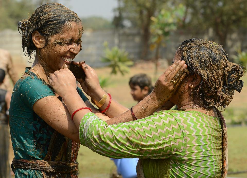 Indian women play with fresh cow dung mixed with cow urine as they celebrate the Holi festival on the outskirts of Ahmedabad in India’s west in 2018. Source: Getty Images